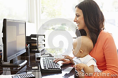 Hispanic mother with baby working in home office Stock Photo