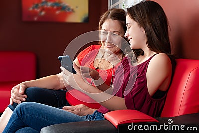 Hispanic teenage girl and her grandmother looking at a smartphone and smiling Stock Photo