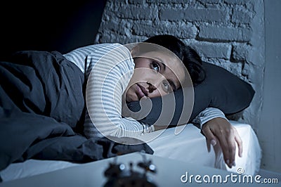 Hispanic woman at home bedroom lying in bed late at night trying to sleep suffering insomnia Stock Photo