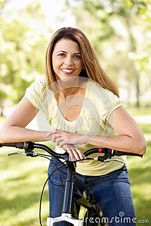 Hispanic woman in park with bike Stock Photo