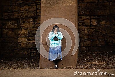 Hispanic Woman Prays By Wall Stock Photo