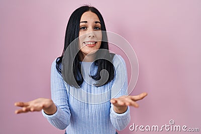 Hispanic woman standing over pink background smiling cheerful offering hands giving assistance and acceptance Stock Photo