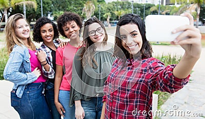 Hispanic woman taking selfie with group of international girlfriends Stock Photo