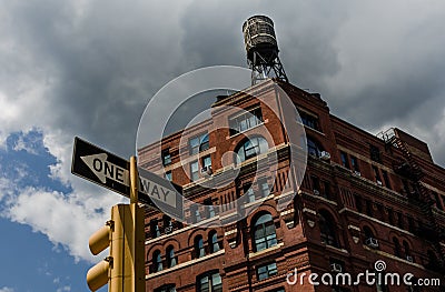 Historic brick building in New York City with water tower on top, stoplight in foreground Stock Photo