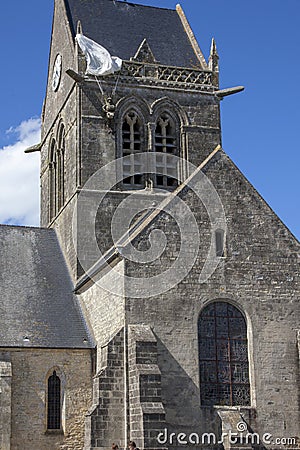 Historic church of Sainte mere l`eglise, with a paratrooper hanging on the bell tower. Editorial Stock Photo