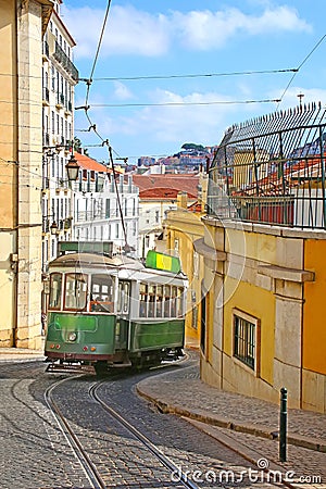 Historic green tram against old town streets, part of the tramway network since 1873, Lisbon, capital city of Portugal Stock Photo