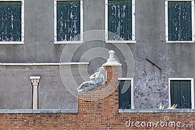 Historic marble figure of a beautiful woman at a fence with closed shutter in background at island of Burano, Venice Stock Photo