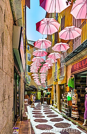Historic tenement houses and narrow streets decorated with pink umbrellas of old town in perfumery city of Grasse in France Editorial Stock Photo