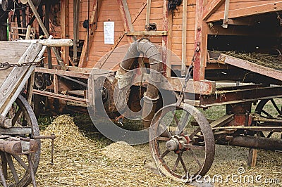 Historic threshing machine in operation. In the foreground is a historic wooden cart for the mown wheat Stock Photo