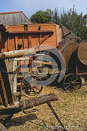 Historic threshing machine with subsequent straw press in operation. In the foreground is a historic wooden cart for the mown Stock Photo