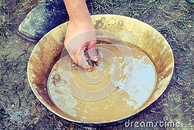 Historical reconstruction of prospector by hand, retro. A man stands next to a tray for washing gold sand. Washing of gold in tray Stock Photo