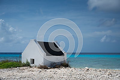 Historical white slave house on a beach under a cloudy sky in Bonaire Stock Photo