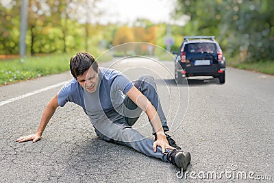 Hit and run concept. Injured man on road in front of a car Stock Photo