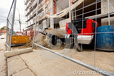 Metal trailer coupling of compressor peeks through wire fence on construction site Stock Photo