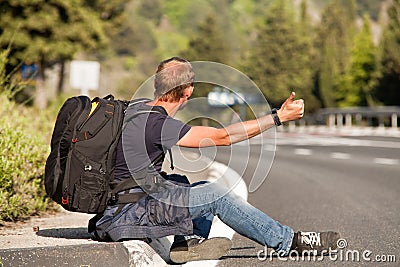 Hitchhiker man traveler sitting on the roadside Stock Photo