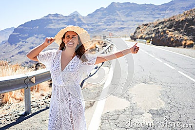 Hitchhiking woman travelling by hitchhike on road side, smiling happy on summer vacation Stock Photo