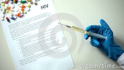 HIV word written on conclusion, hand with syringe, pills and tablets on table Stock Photo