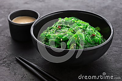 Hiyashi Wakame Chuka seaweed salad with sesame seeds in a black bowl and peanut sauce Stock Photo