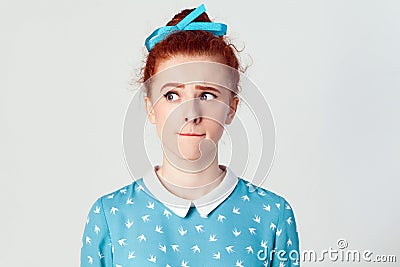 Hmm. Let me think. isolated studio shot on gray background of cute redhead girl with looking sideways and planning something Stock Photo