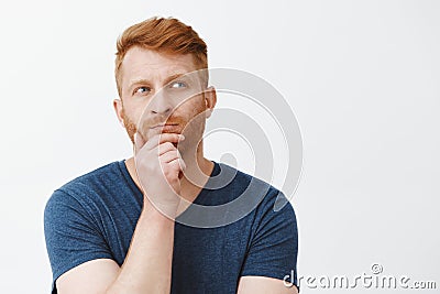 Hmm let us think. Portrait of focused creative and smart good-looking male strategist with red hair, standing in Stock Photo
