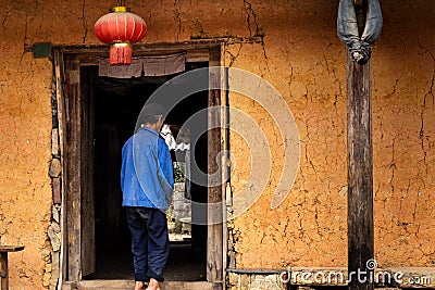 Unrecognisable hmong farmer entering a traditional hmong house with a chinese lantern hanging in Ha Giang Province, Vietnam Editorial Stock Photo