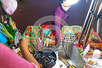 Vietnamese woman selling seafood on the counter and Snail`s for sale in a night market in Ho Chi Minh city Saigon, Vietnam. Foo Editorial Stock Photo