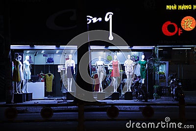 Women dresses displayed on dummies in front of a fashion store. Young Asian saleslady Editorial Stock Photo