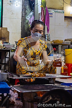 Ho Chi Minh City, Vietnam- November 9, 2022: Street food store in the streets of Saigon. Female chef cooking or bbq on open fire, Editorial Stock Photo