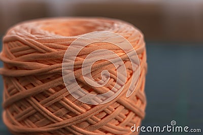 A coil of large knitted yarn of peach color on the blure backgroud Stock Photo