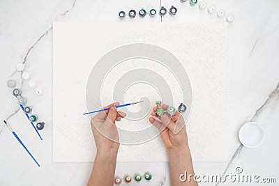 hobby at home painting by numbers to draw from above a view of women's hands holding cans of paints Stock Photo
