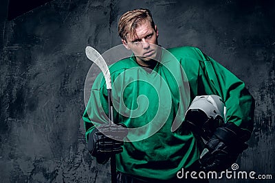 Hockey player holds protective helmet and playing stick on grey Stock Photo