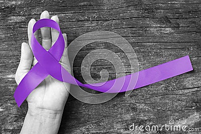 Hodgkin`s lymphoma and testicular cancer awareness violet ribbon symbolic bow color on helping hand support and aged wood Stock Photo