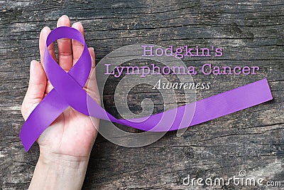 Hodgkin`s lymphoma and testicular cancer awareness violet ribbon symbolic bow color on helping hand support isolated Stock Photo