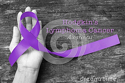 Hodgkin`s lymphoma and testicular cancer awareness violet ribbon symbolic bow color on helping hand support isolated Stock Photo