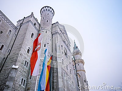 HOHENSCHWANGAU, GERMANY - 23 FEBUARY 2018: Neuschwanstein Castle in winter Close-up. Germany and EU flag.The destination famous ca Editorial Stock Photo