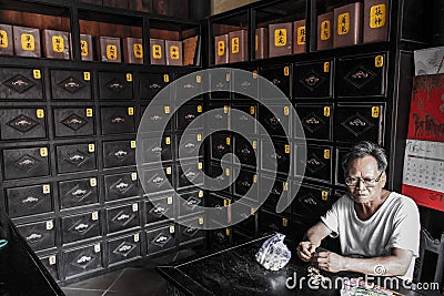 Old man eating peanuts in an old pharmacy, Hoi An, Quáº£ng Nam Province, Vietnam Stock Photo