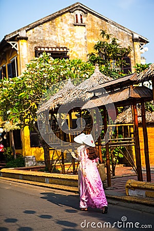 HOI AN, QUANG NAM, VIETNAM, April 26th, 2018: Vietnamese women wearing ao dai. Street view with old houses in Hoi An ancient town. Editorial Stock Photo