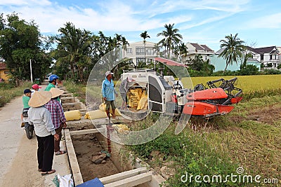 A group of people next to a rice harvester during the first rice harvest of 2021 in Hoi An, Vietnam Editorial Stock Photo