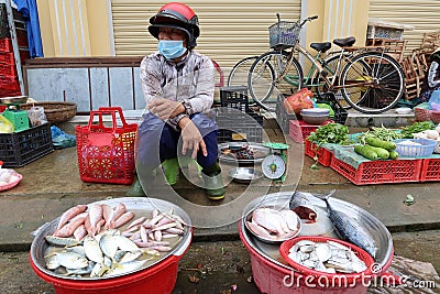 A man with a helmet and mask at a small stall in the Ba Le market in Hoi An Editorial Stock Photo