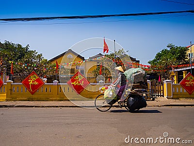 HOIAN, VIETNAM, SEPTEMBER, 04 2017: Unidentified woman biking in the street view with old houses, and colorful lanters Editorial Stock Photo