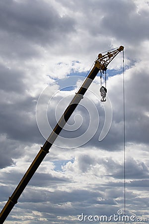 Hoisting crane at a construction site against a cloudy sky Stock Photo