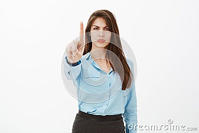 Hold on, wait a sec. Bossy displeased attractive entrepreneur in blue official blouse, frowning and pulling index finger Stock Photo