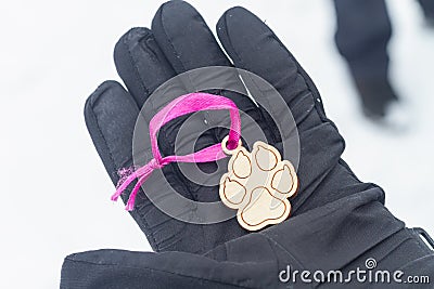 Hold in your hand a wooden keychain in the shape of a dog& x27;s paw as a symbol of love for dogs Stock Photo