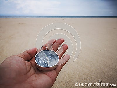 Holding a compass showing the direction point to north and facing the ocean. Stock Photo