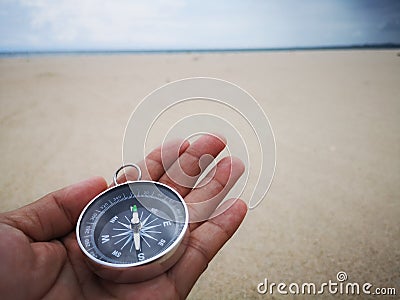 Holding a compass showing the direction point to north and facing the ocean. Stock Photo