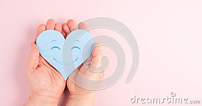 Holding a heart with a smiling face, colorful background with copy space, valintines day Stock Photo