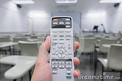 Holding remote control projector in hand in classroom Stock Photo