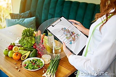 Holding schematic meal plan for diet with various healthy products on the background. Weight loss and right nutrition concept. Stock Photo
