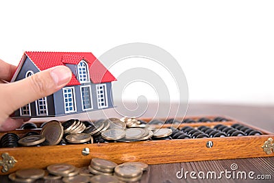 Holding a small house model, beads and scattered euro coins Stock Photo