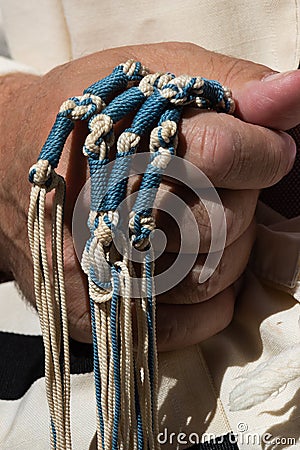 Holding techelet blue tzitzit strings during Jewish prayer Stock Photo